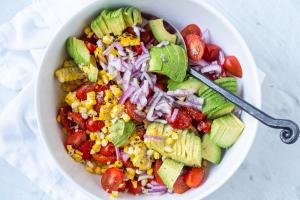 Corn Tomato Avocado Salad in a bowl with dressing