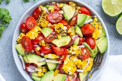 Corn Tomato Avocado Salad in a bowl and limes