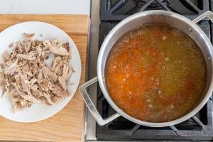 pot with carrots and broth, chicken in a plate