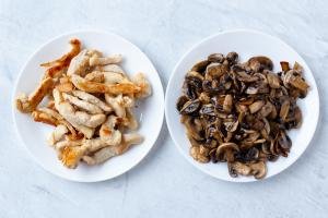 Two plates, one with mushrooms and one with chicken