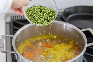 peas getting added to the cooking split pea soup
