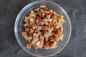 Cooked bacon in a bowl cut into pieces.