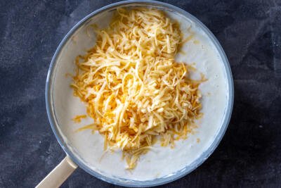 Cheese added to creamy mac and cheese sauce.