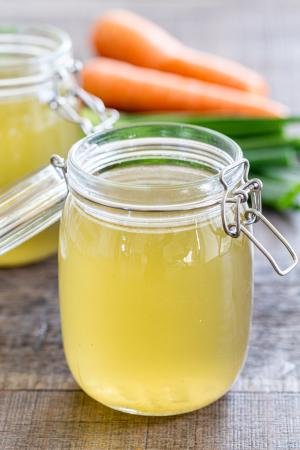 Homemade Chicken Broth in jars that are standing on a cutting board