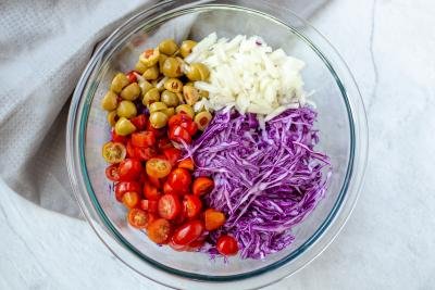 Purple cabbage, olives, tomatoes and onions in a bowl