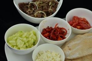 Bowls with ingredients for the pita pockets in each bowl; cucumbers, feta cheese, tomatoes, peppers and beef