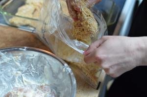 Chicken being moved from marinate into cheese and seasoning mixture