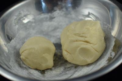 Pie dough split into 2 balls, 1 slightly bigger then the other, placed into the same bowl