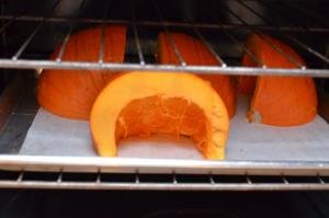 Pumpkin cut into 4 pieces on a baking sheet placed into the oven