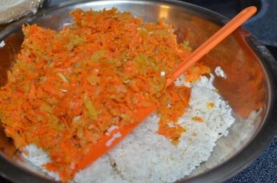 Sautéed carrots and onions being combined with white rice in a bowl