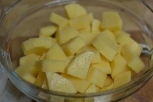 Peeled potatoes diced into small cubes in a bowl