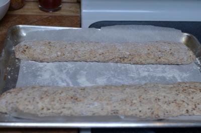 2 raw baguettes placed on a baking sheet lined with parchment paper that is floured