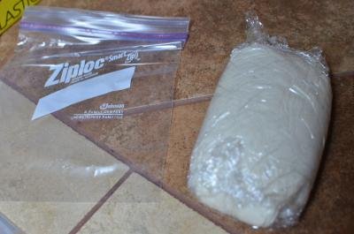 Pizza Dough rolled in placed wrap and being placed into a ziploc bag