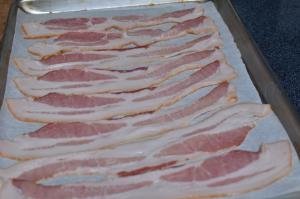 Bacon layer out on a baking sheet that is lined in parchment paper
