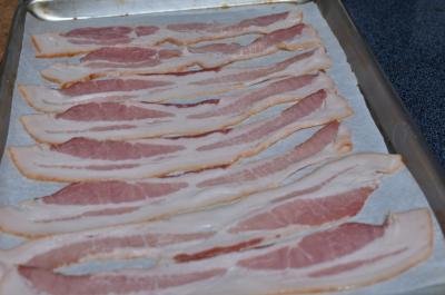 Bacon layer out on a baking sheet that is lined in parchment paper