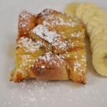 Baked French Toast on a plate with powdered sugar sprinkled on top and a row of banana slices
