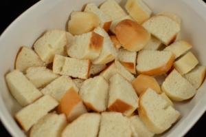 White bread sliced into 1inch squares placed on a ceramic baking pan
