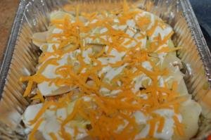 Sliced potatoes with cream and cheese in baking sheet