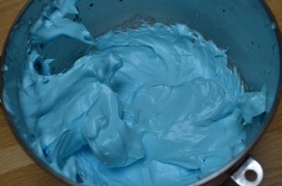 Egg white and sugar mixture colored with blue food coloring in the mixing bowl