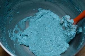 Blue colored whipped egg whites and sugar being stirred together with flout and sugar dry mixture