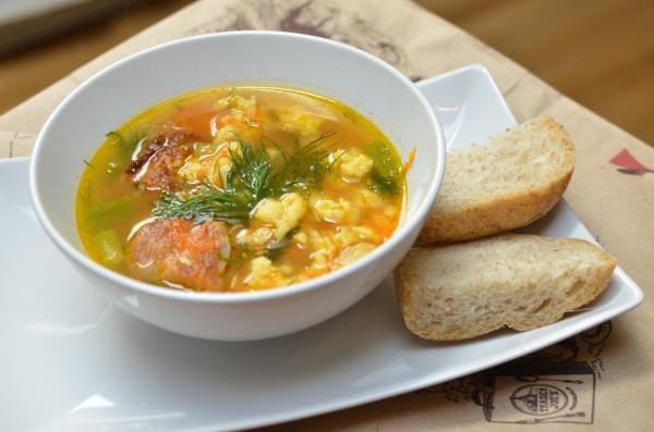 Egg Noodle Soup in a bowl on a plate with 2 bread slices on the side