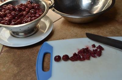 Drunken cherries being cut up into small pieces on a cutting board