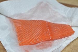 Salmon being wiped on both sides with a paper towel