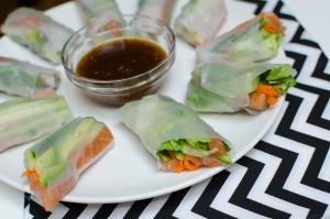 Spring Rolls With Salmon cut in half on a plate with sauce in the middle of the plate