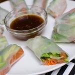 Spring Rolls With Salmon on a plate with little bowl of sauce in the middle of the rolls