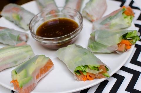 Spring Rolls With Salmon on a plate with little bowl of sauce in the middle of the rolls
