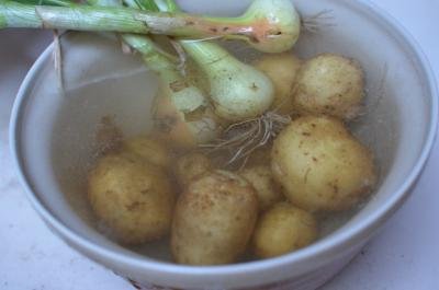 Potatoes and onions soaking in a bowl filled with water