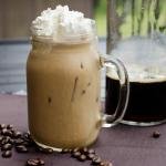 Cold-Brew Coffee in a mason jar cup with whipped cream on top and coffee beans around the bottom of the cup