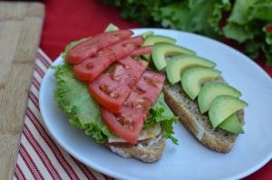 Garlic Toasted Sandwich halves with meat, cheese, lettuce, tomato, and avocado on a plate