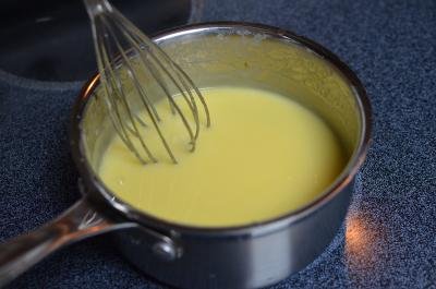Sugar, margarine and milk being whisked on a stove top in a saucepan