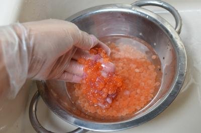 Caviar in strainer being washed with water in a sink