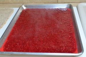 Gelatin raspberry mixture spread on a baking sheet lined with a silicon mat