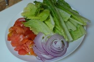 On a plate cut up tomatoes, purple onions and lettuce