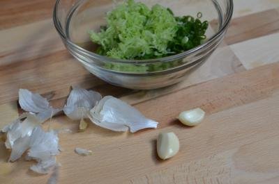 Scallions and grated cucumber in a bowl with garlic next to the bowl