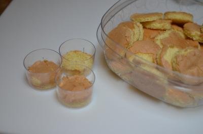 Sponge cake cut into small circles and placed into small cups and a container filled with them