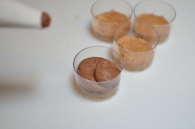 Chocolate mousse mixture being placed on top of the sponge cake in small cups