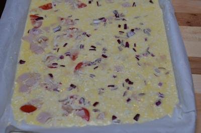 Omelette Roll mixture poured over a baking pan that is lined with parchment paper