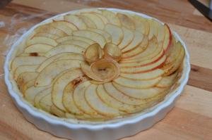 Apple slices placed over the top of the pie to form a swirl shape with a flower inside also made of apple slices
