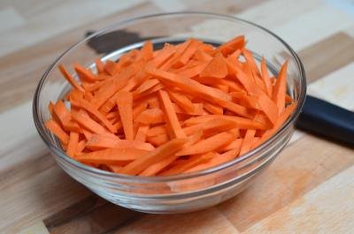 Carrots that have been cut into thin strips all placed into a bowl