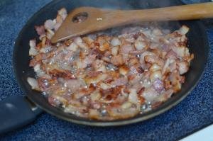 Bacon being fried until crispy in frying pan