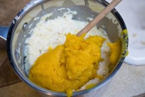 Pumpkin puree being mixing in a saucepan with millet, rice and milk mixture