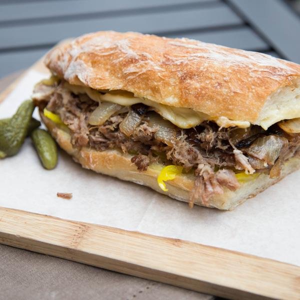 Cuban Pork Sandwich cut in half on a cutting board lined with parchment paper