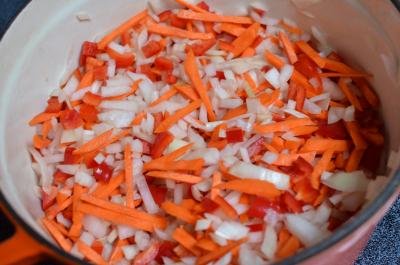 Onions, carrots and bell peppers all mixed together in a dutch oven