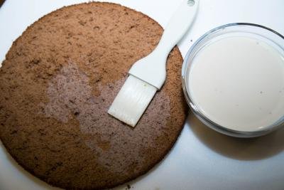 Whipping cream and liquor mixture being placed on each cake layer