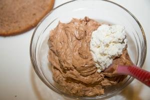 Whipped cream and chocolate mixture being combined in bowl with a spatula