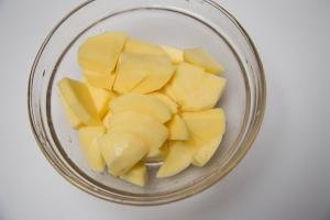 A bowl with peeled and cut up potatoes
